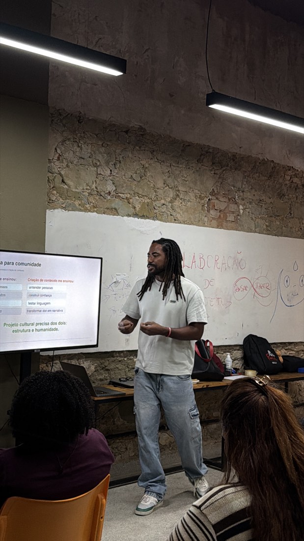 denison luz falando de pé ao lado da tela, que mostra o slide sobre o que a criação de conteúdo ensina